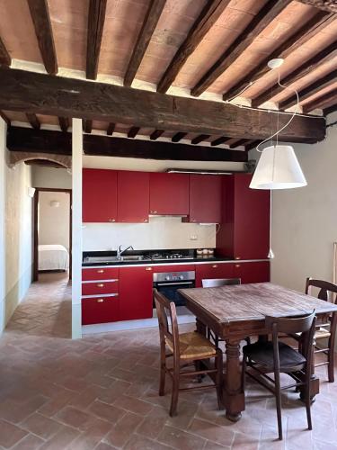 a kitchen with red cabinets and a wooden table at Rocca d'Orcia Suites and Villas in Castiglione dʼOrcia