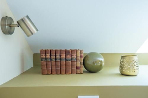 a shelf with books and a lamp and a vase at le petit logis in Trélazé
