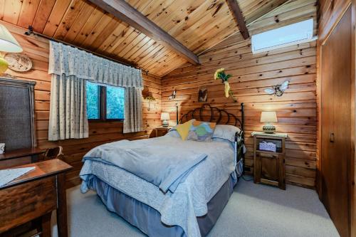 ein Schlafzimmer mit einem Bett in einer Blockhütte in der Unterkunft Rustic Waterfront Cottage W Hot Tub in Lions Head