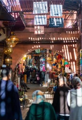 a group of people walking through a market with lights at Dar Mima in Fès