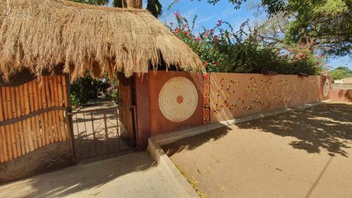 a gate to a house with a straw roof at LE BENTENIER Home Détente in Nianing
