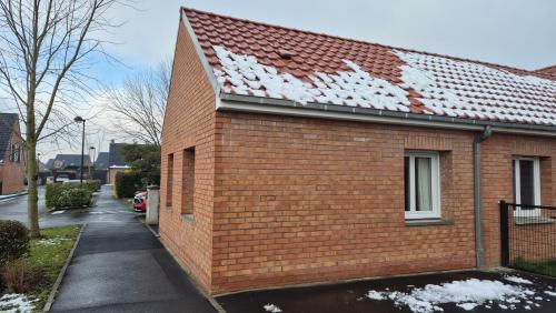 a red brick house with snow on the roof at L'Écrin de Sérénité in Wervicq-Sud