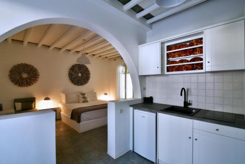 a kitchen with white cabinets and a bed in a room at Myrto Bungalows in Artemonas