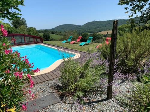 - une piscine dans un jardin avec des chaises et des fleurs dans l'établissement Les Charmes de Boubène, à Saint-Marcet