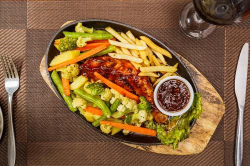 a plate of food with meat and vegetables and french fries at Hotel Travellers Nest Kandy in Kandy