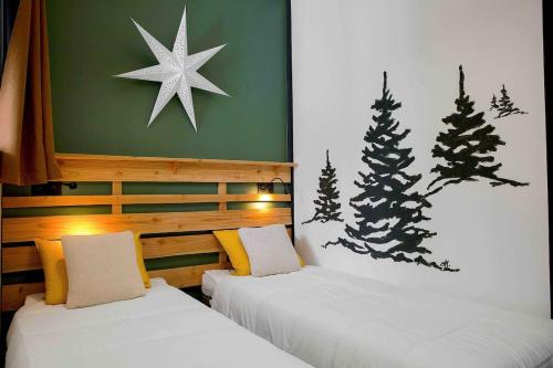 deux lits dans une chambre avec des sapins de Noël au mur dans l'établissement Nid douillet avec balcon, à Le Mont-Dore