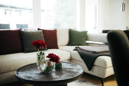 a living room with a couch and a table with red flowers at Feel Home Apartments 501 - Seeblick - Bergblick - Parkplatz in Emmetten