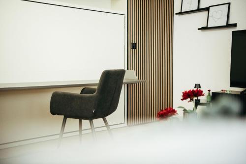 a black chair in a room with a table and flowers at Feel Home Apartments 501 - Seeblick - Bergblick - Parkplatz in Emmetten