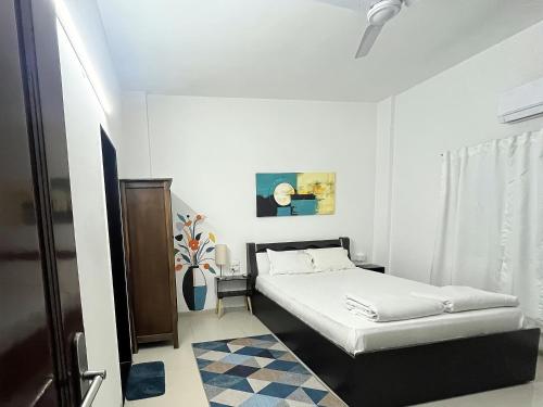 プネにあるHOSHTEL99 - LUX - Stay, Cowork and Cafe - Luxurious Bungalowの白いベッドルーム(ベッド1台、ラグ付)