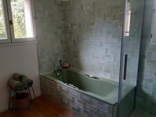 La salle de bains est pourvue d'une baignoire verte et d'une douche en verre. dans l'établissement Spacious villa pool sea view 7 people 4 bedrooms, à Tourrettes-sur-Loup