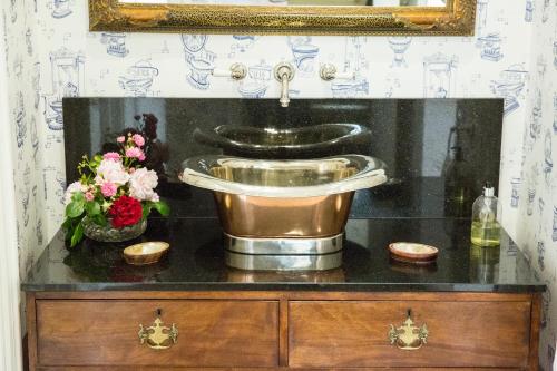 a bathroom with a sink and flowers on a counter at Prince Hill House in Devizes