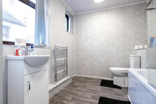 a white bathroom with a sink and a toilet at Superior 4-Bedroom Home ideal for families, Contractors and Relocations in Stoke on Trent