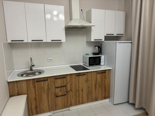 a kitchen with white cabinets and a sink and a microwave at 41-40 этаж Отель Bon Dian in Astana