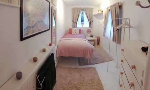 a small bedroom with a pink bed in it at Centrel to london single bed room quiet home with host and breakfast in London