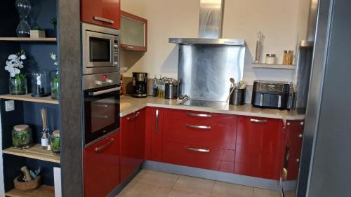 une cuisine avec des armoires rouges et un micro-ondes dans l'établissement Maison de village 3 chambres vue mer, à Santa-Reparata-di-Balagna