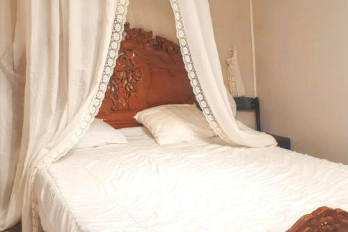 - un lit à baldaquin avec des draps et des oreillers blancs dans l'établissement Appartement charmant à La Grande-Motte de 37m² avec jardin, à La Grande Motte