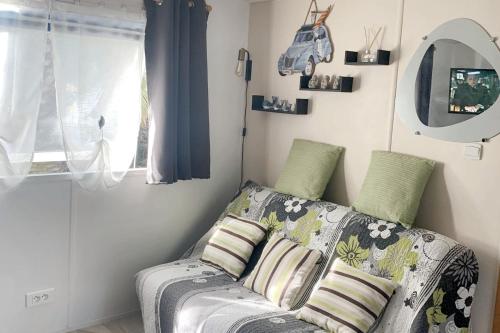 un salon avec un canapé et une fenêtre dans l'établissement Bungalow charmant à Agde, piscines, au Grau-dʼAgde