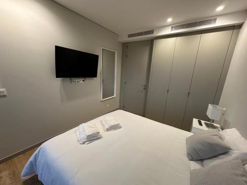 a bedroom with a white bed with a tv on the wall at New Douro 801 with parking in Vila Nova de Gaia