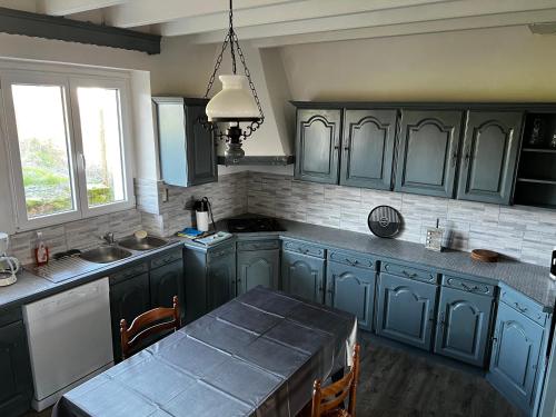 d'une cuisine avec des placards bleus et une table. dans l'établissement Corps de ferme, à La Réorthe