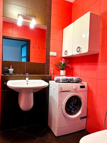 a red bathroom with a washing machine and a sink at LUX apartament in Warsaw