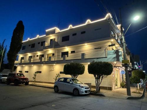 a white car parked in front of a building with lights at Hotel Fratelli in Aguascalientes