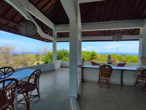 a porch with a table and chairs and a view of the ocean at Mimpi Bungalow 3A in Kubutambahan