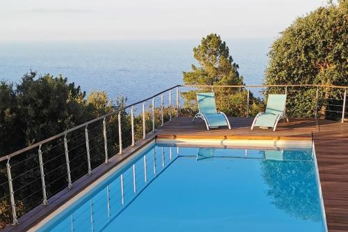 コンカにあるMagnifique villa - superbes vues Mer et Montagneの海を望むデッキ(椅子2脚付)のスイミングプールを利用できます。