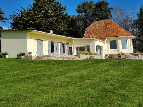 une maison avec une pelouse verte devant elle dans l'établissement Les Neyes, à Binic