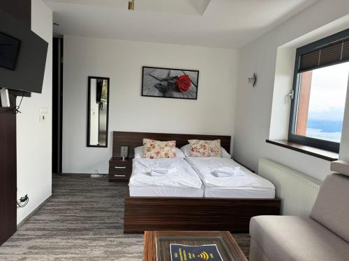 a bedroom with a bed and a couch and a window at Apartman Panorama 1001 in Štrbské Pleso