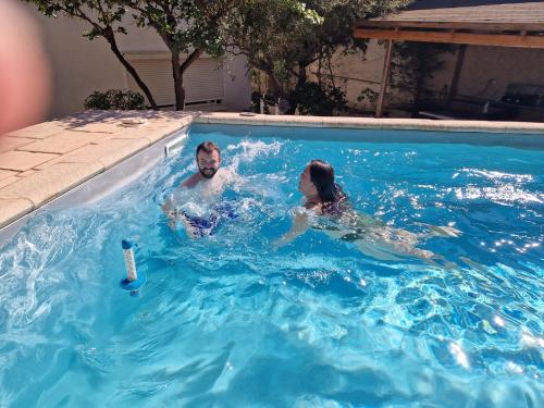 a man and woman swimming in a swimming pool at Appartement spacieux T3 neuf in Cassis