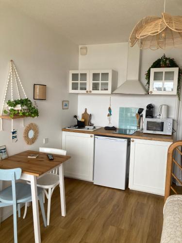 une cuisine avec des armoires blanches et une table en bois dans l'établissement Studio du vieux port, à Quiberon