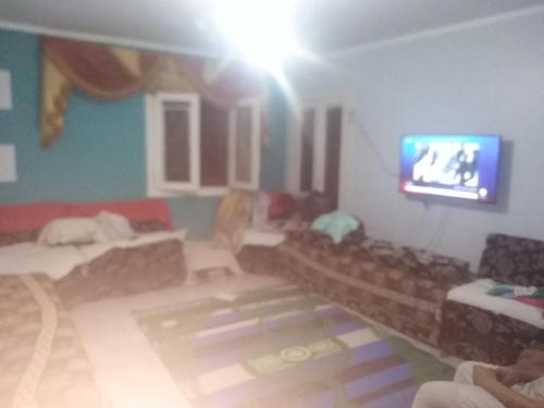 a living room with couches and a flat screen tv at Minya House in Sawādah