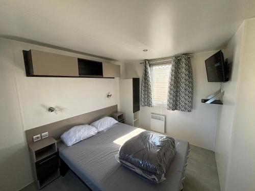 a bedroom with a bed with two pillows on it at Lodge du Sangla Mobil Home premium Village Vacances 4 étoiles Lège Cap Ferret in Lège-Cap-Ferret