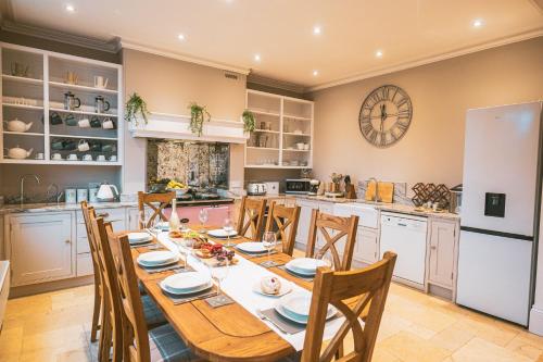 a kitchen with a table and chairs and a clock on the wall at St Michaels Town House - Elegant and Large Holiday Home in the Heart of Gloucester in Gloucester