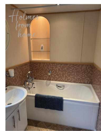 a bathroom with a tub and a sink at Holmes from Home - 106 Sunrise Southview in Winthorpe