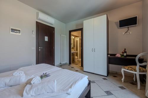a bedroom with a white bed and a tv at Villa Maddalena in Bardolino