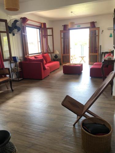 a living room with red couches and a wooden floor at Maison familiale à Ile Maurice in Mahébourg