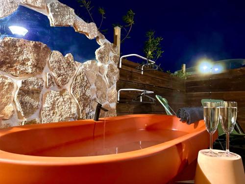 an orange bath tub with a wine glass next to it at Superbe Maison - Bain Chaud ou Froid & Cinema - Cap d'Agde in Cap d'Agde
