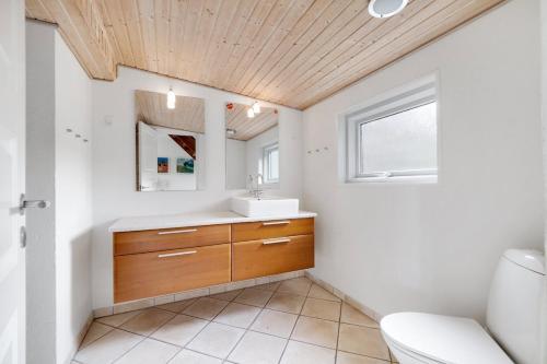 Un baño con lavabo, inodoro y ventana. en Jørgen's Feriehus, en Lemvig