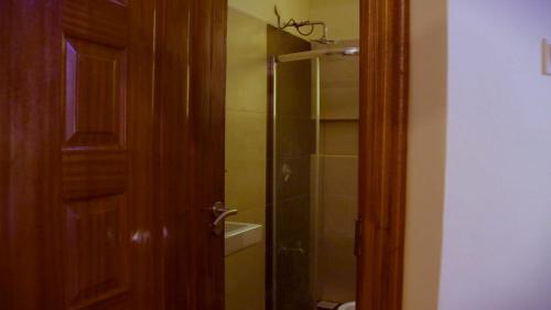 a bathroom with a shower and a toilet and a door at La Casa Savanna in Naivasha