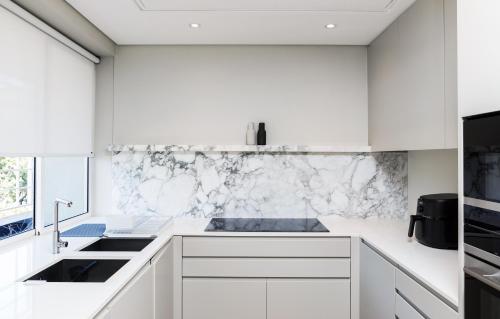 a white kitchen with white cabinets and a sink at 401 Dovenby in Cape Town