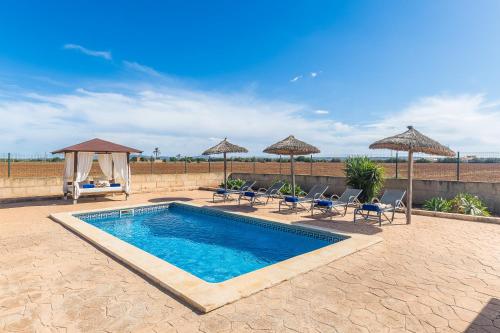 a swimming pool with chairs and umbrellas on a patio at Son Sea Villa in Campos