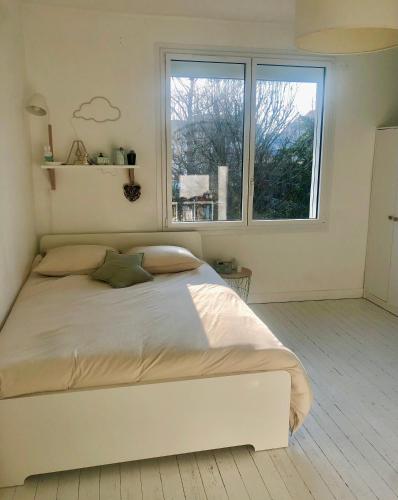 une chambre blanche avec un grand lit et une fenêtre dans l'établissement Maison nantaise avec piscine proche du centre ville, à Nantes