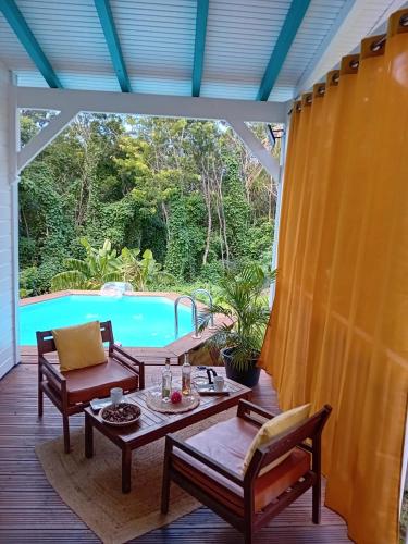 a patio with a table and chairs and a pool at Rayon de soleil in Deshaies