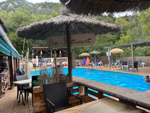 - une piscine avec un parasol en paille, une table et des chaises dans l'établissement Camping domaine Saint Martin 4 étoiles, à Casteil