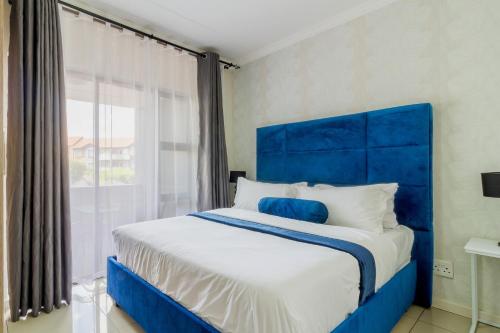 - un lit bleu dans une chambre avec une grande fenêtre dans l'établissement Buckingham Palace 2 Bed 2 Bath, à Midrand