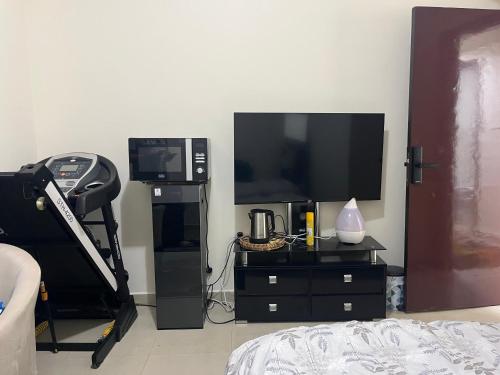 a living room with a television and a dresser with a bed at SHJ DXB Sunny Border Guesthouse in Dubai