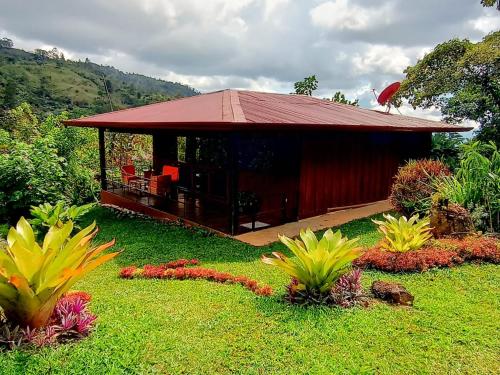 a small cabin with a red roof in a garden at Aloha chirripo cabaña familiar in Convento