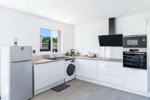 Una cocina blanca con fregadero y lavavajillas. en ""Villa One"" 80 m2 avec Jacuzzi, en Saint-Mitre-les-Remparts