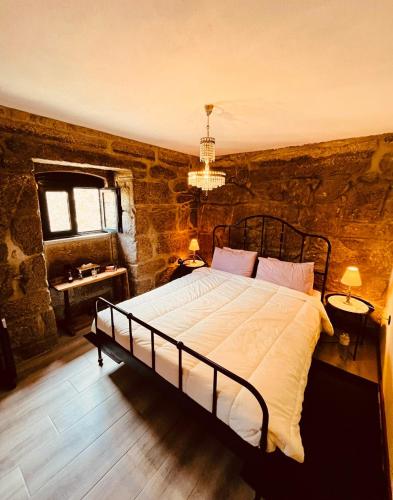a bedroom with a large bed in a stone wall at Casa da Renda in Campos